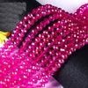 A close-up of bright pink faceted rondelle glass beads arranged in strands.