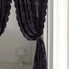A dark purple sheer curtain with floral embroidery is draped in a window frame.