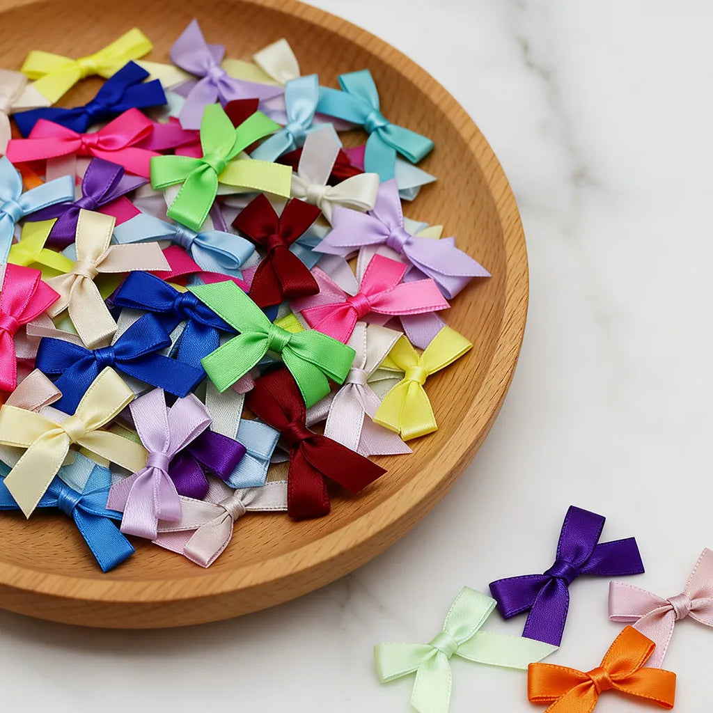 A collection of small satin ribbon bows in various pastel and jewel tones arranged on a wooden plate.