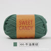 A ball of olive green hand-dyed fabric strip yarn labeled Sweet Candy for yarns