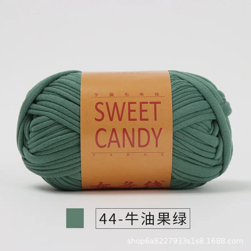 A ball of olive green hand-dyed fabric strip yarn labeled Sweet Candy for yarns