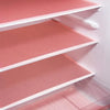 A close-up view of pink reusable EVA fridge shelf liners installed in a white shelving unit.