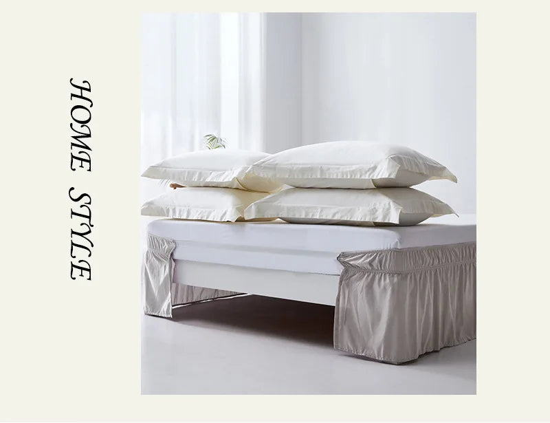 A white bed with an elegant ruffled skirt set featuring soft, light-colored linens and pillows.