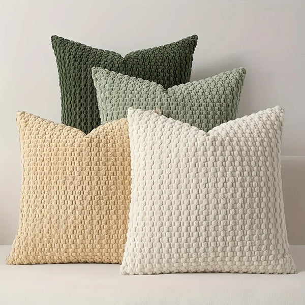 A collection of decorative pillow covers in shades of green and cream, featuring a textured, quilted pattern.