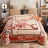 A beige weighted blanket with a floral pattern and orange trim is displayed on a bed.