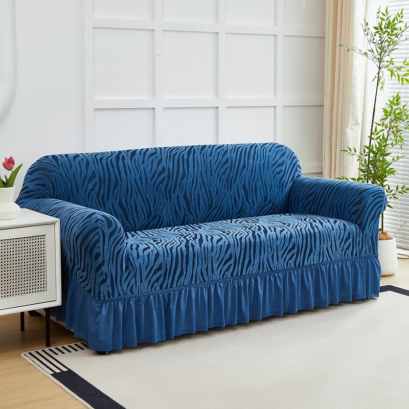 A deep blue anti-slip jacquard sofa slipcover is displayed on a light rug in a bright room.
