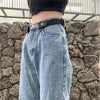 A close-up of a pair of light blue denim jeans with a black invisible stretch belt worn over the waistband.