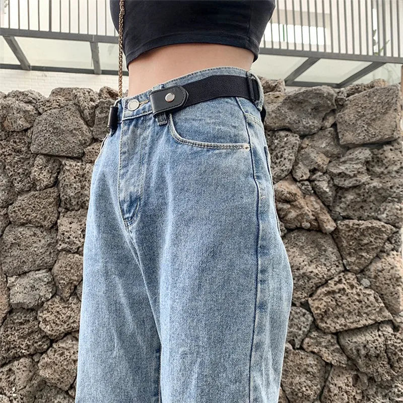 A close-up of a pair of light blue denim jeans with a black invisible stretch belt worn over the waistband.