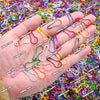 A hand holds a collection of colorful gourd-shaped locking safety pins for knitting and sewing.