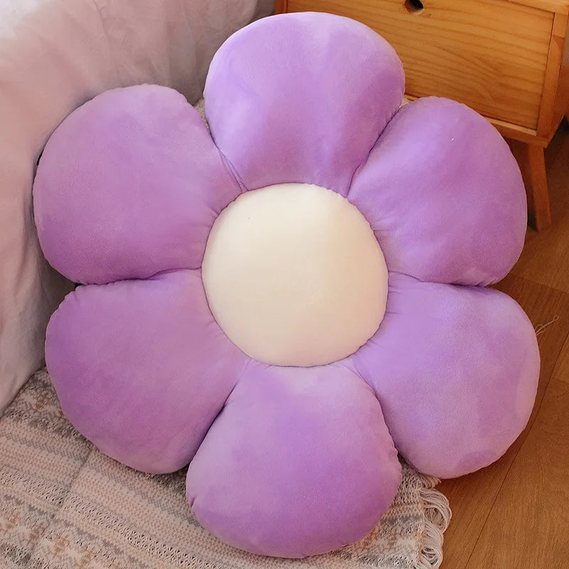 A purple sunflower plush flower cushion resting on a light-colored textured fabric.