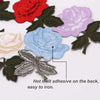 A set of colorful embroidered iron-on patches featuring roses in shades of red, purple, and blue on dark green fabric.