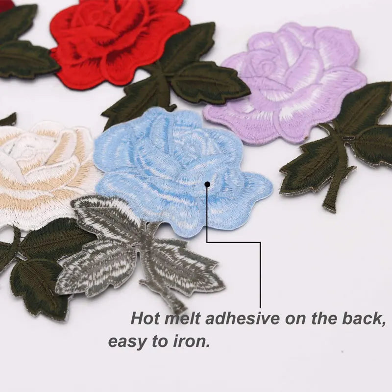 A set of colorful embroidered iron-on patches featuring roses in shades of red, purple, and blue on dark green fabric.