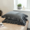 A stack of two soft plaid washed cotton pillowcases with ruffled edges resting on a light surface.