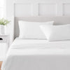 A white bed with a headboard and bedding, featuring a 4-piece microfiber flat fitted sheet set.