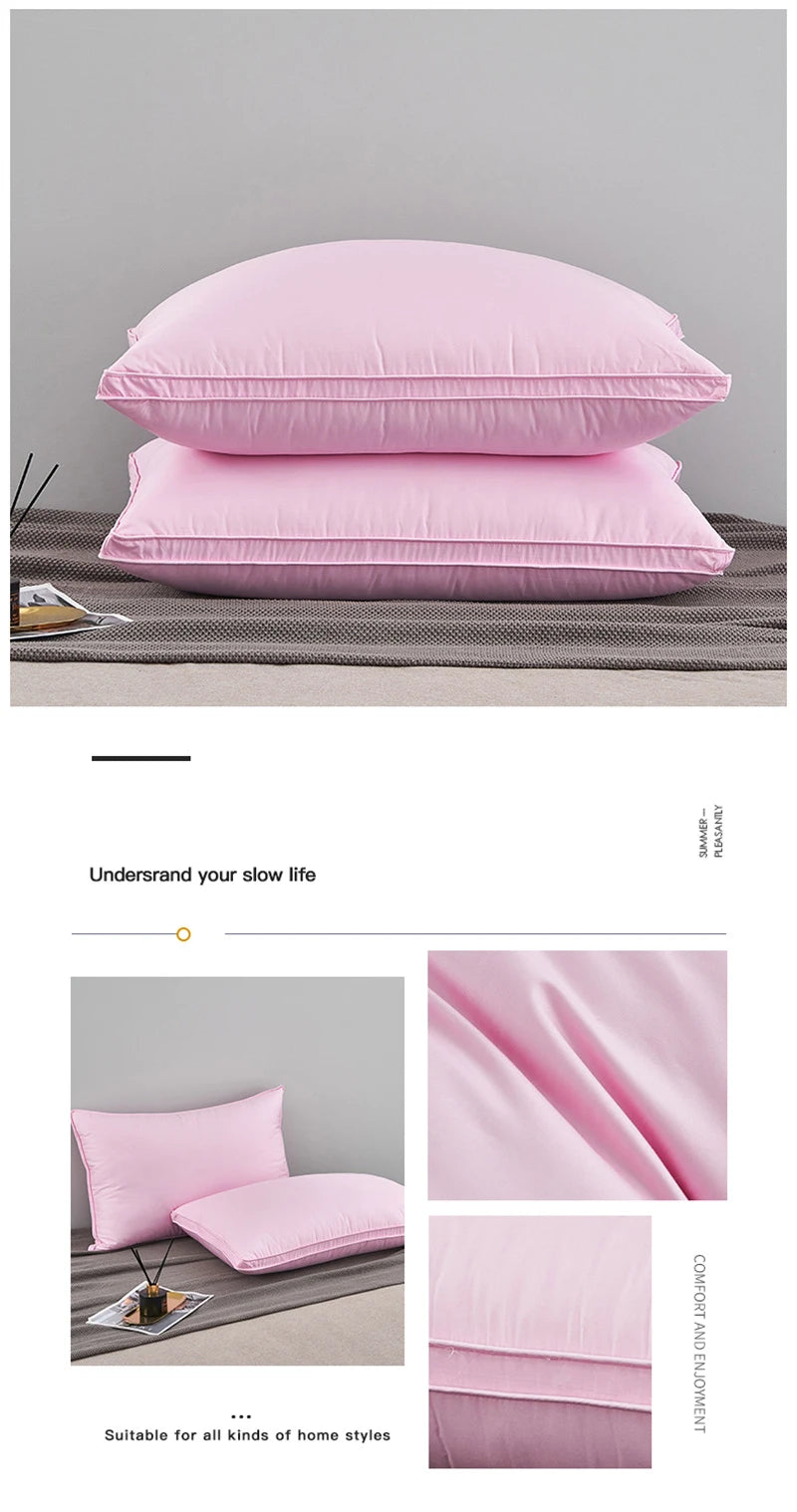 Pink luxury goose down and feather bed pillows stacked on a gray fabric.