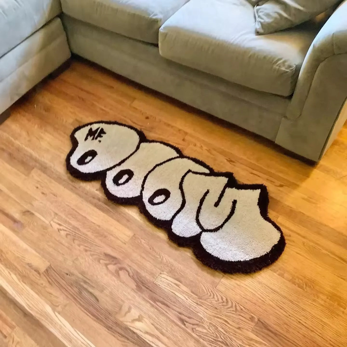 A cute cartoon decorative floor mat shaped like a body lying down on a wooden floor.