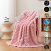 A pink soft flannel throw blanket draped over a chair in a bright room.