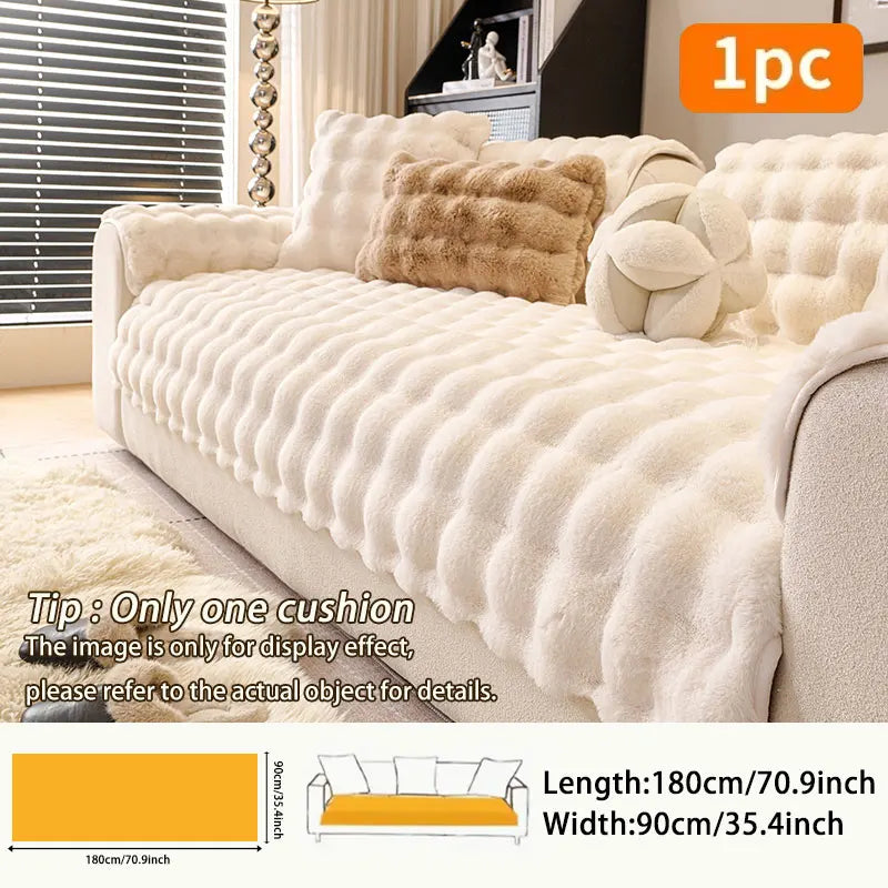A beige plush sofa cushion with decorative fluffy accents displayed on a light-colored sofa.