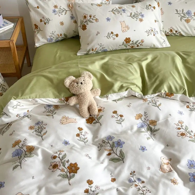A light green and white floral bedding set featuring a teddy bear pillow and duvet.