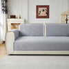 A light gray geometric quilted sofa cushion cover on a white upholstered sofa in a bright room.