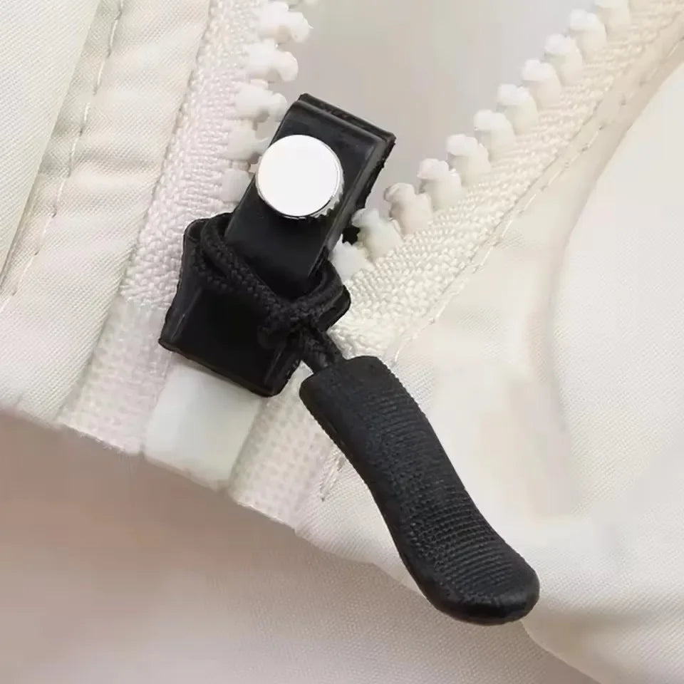 A black zipper repair kit with a silver button and a black pull tab is shown against a white fabric background.