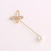 A delicate gold-toned adjustable pearl brooch shaped like a flower with clear stones.