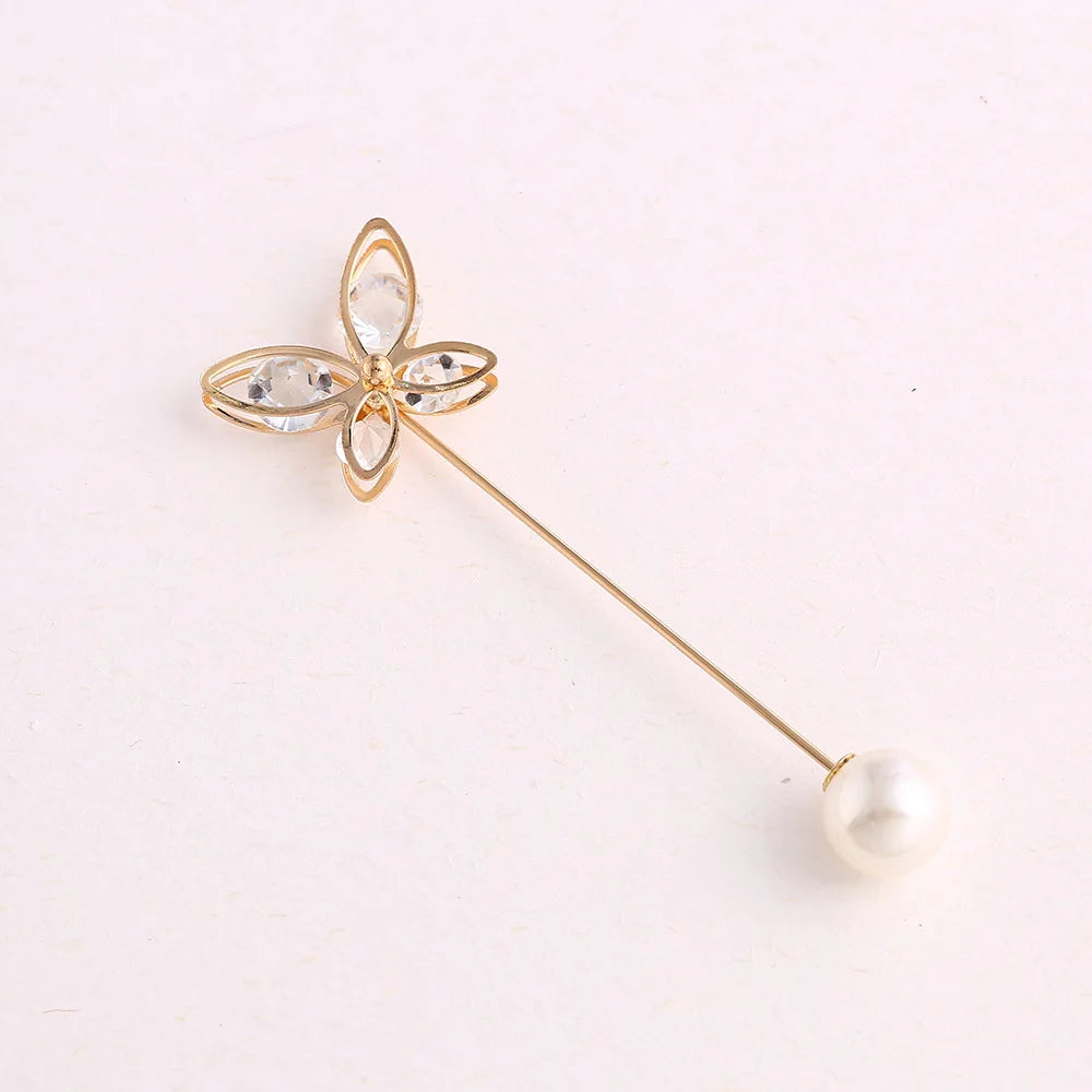 A delicate gold-toned adjustable pearl brooch shaped like a flower with clear stones.