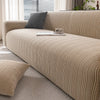 A beige textured sofa slipcover with a dark gray throw pillow and books on the cushion.