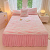 A pink linen bed skirt set featuring striped pink and white bedding and pillows.