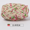 A ball of hand-dyed fabric strip yarn featuring a pink floral pattern on a cream background.