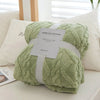 A light green plush double-sided throw blanket with a textured jacquard pattern is presented on a white surface.