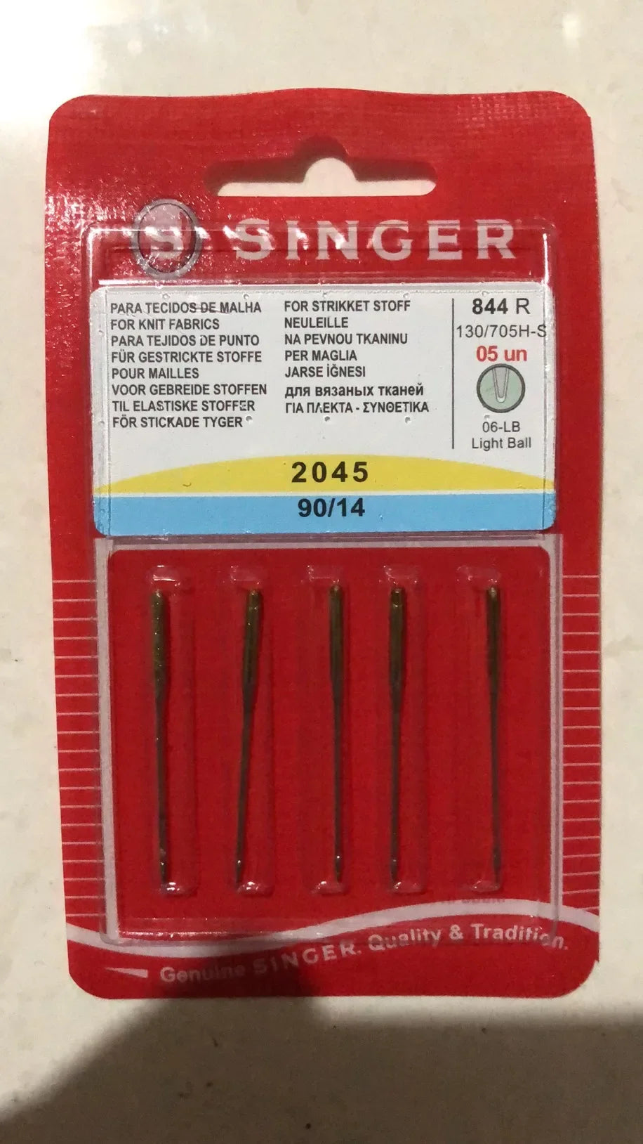 A red packaging box for a Singer sewing needle set labeled 844 R with various language descriptions.