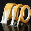 Rolls of yellow no-sew hem tape with clear adhesive strips shown on a reflective surface.