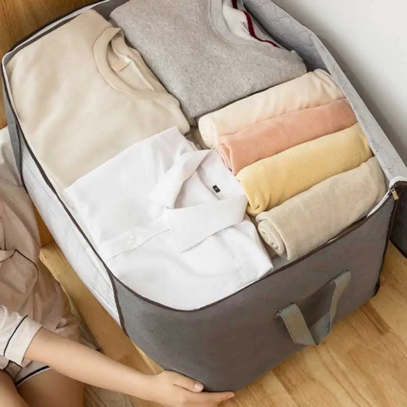A gray storage bag is open, displaying folded clothing and a quilted item inside.