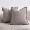 Two solid gray textured boucle throw pillows resting on a light-colored sofa.