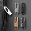 A set of metal zipper pulls in silver, black, and rose gold are displayed against a dark gray fabric background.