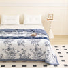 A white floral summer duvet set featuring blue accents and a patterned cover on a bed.