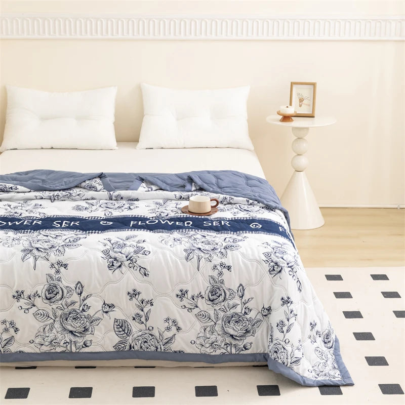 A white floral summer duvet set featuring blue accents and a patterned cover on a bed.