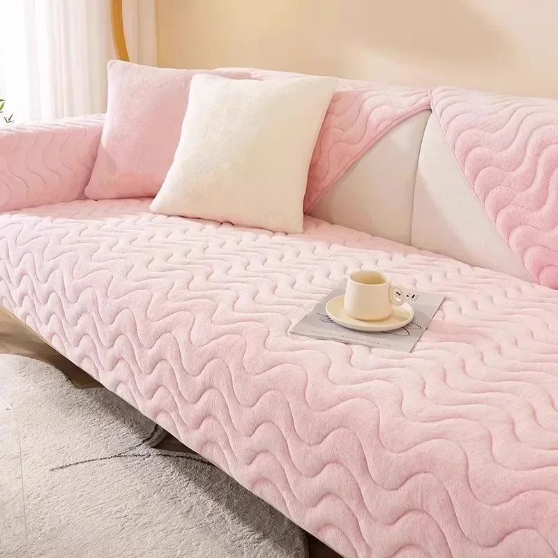 A pink plush sofa seat cushion cover with white accent pillows and a cup on the fabric.