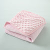 A pink, quilted fleece swaddle blanket folded neatly on a light gray surface.