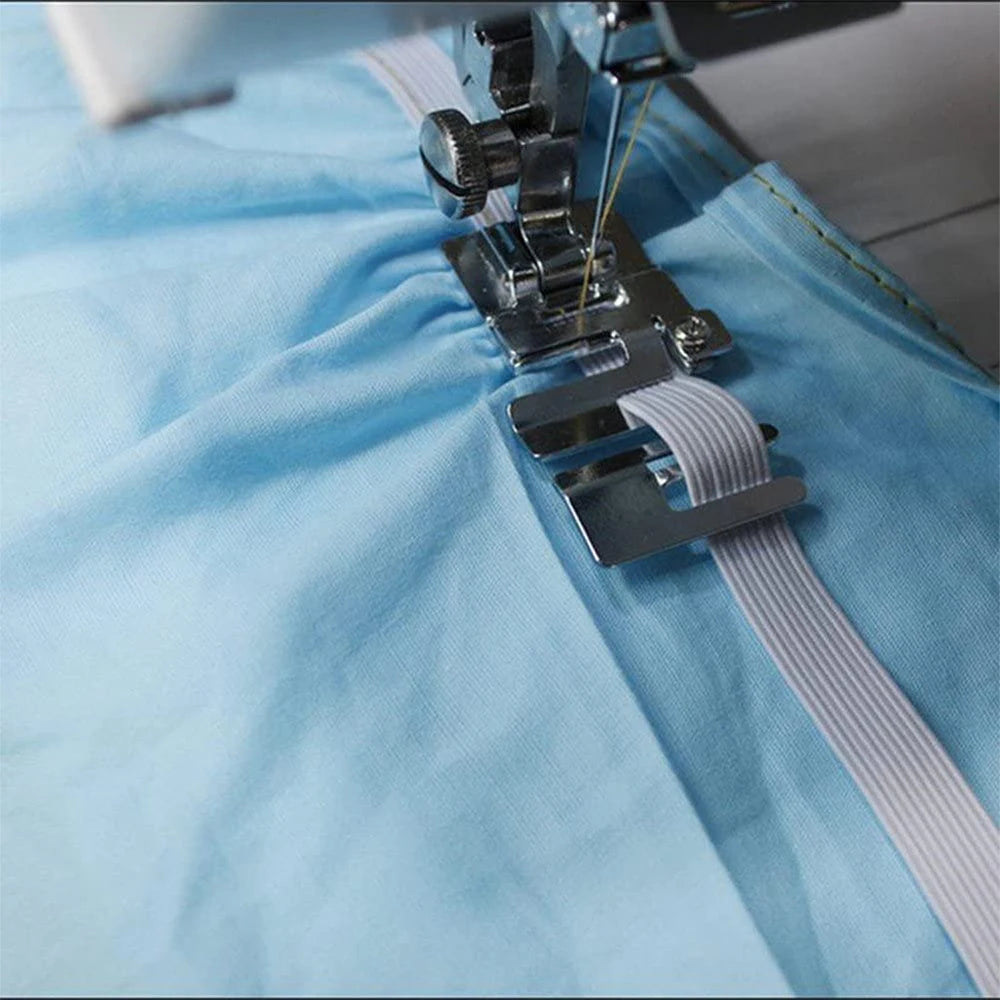 A close-up of a silver stretch fabric presser foot attached to a white sewing machine needle on light blue fabric.