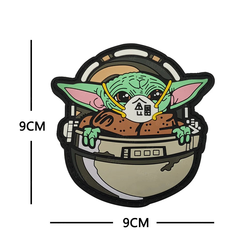 A patch featuring a green alien face inside a circular border, measuring 9cm by 9cm.