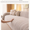 A light beige one-piece blanket draped over a sofa, showing its smooth texture and woven pattern.