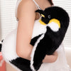A black and white plush toy of a penguin with yellow accents being held by a person.