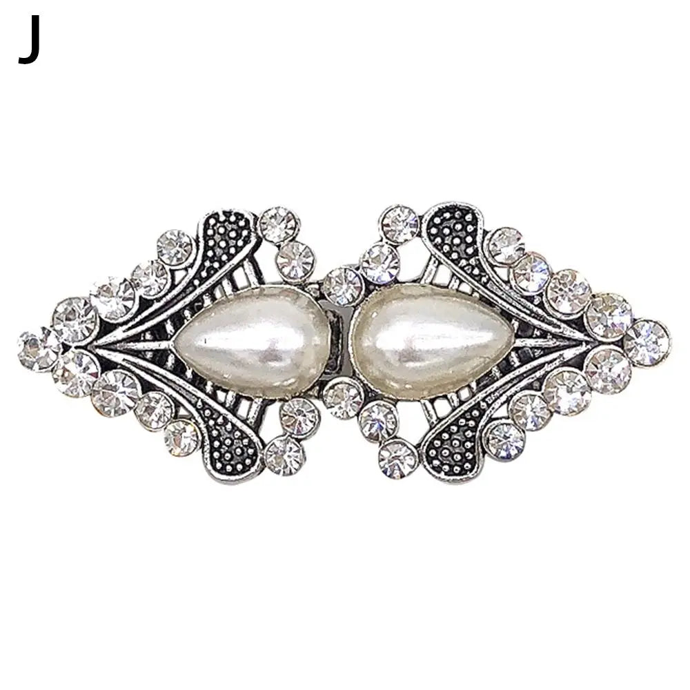 Vintage swirl clip brooch featuring a large pearl surrounded by clear rhinestones and silver-toned metalwork