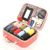 A portable sewing kit in a pink box featuring a mirror, scissors, needles, and various colored threads.