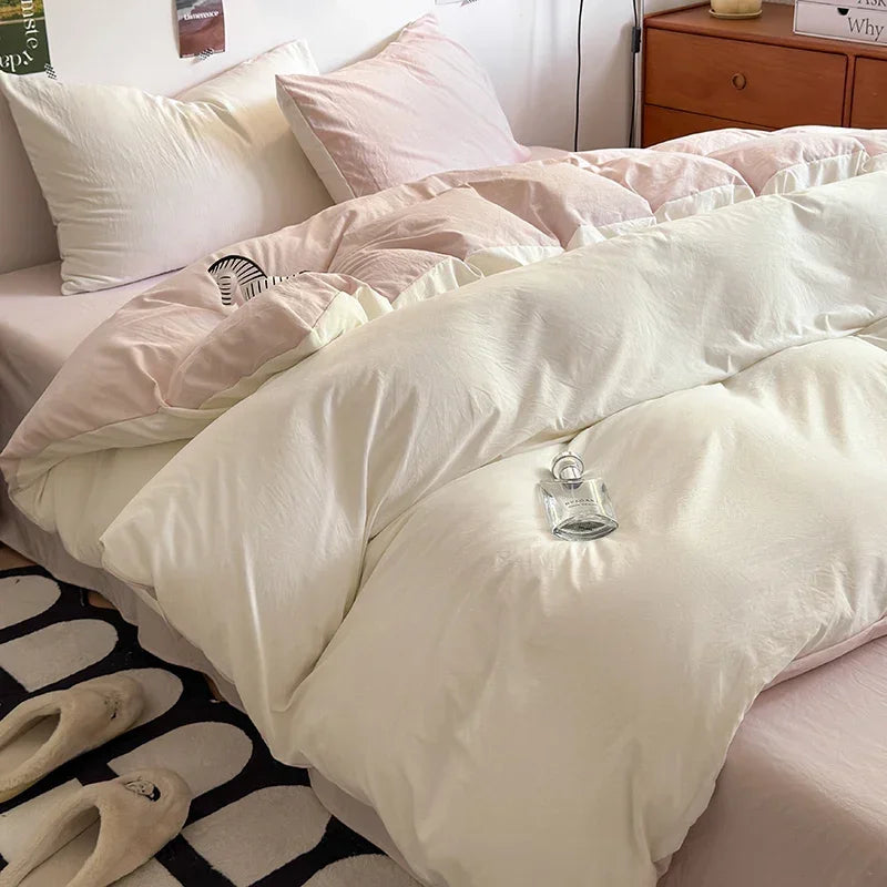 A close-up of a bed covered in ultra-soft washed cotton bedding set featuring white and pale pink pillows and duvet.