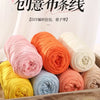 A wooden box filled with various spools of hand-knitted colored yarn in shades of pink, orange, yellow, and cream.