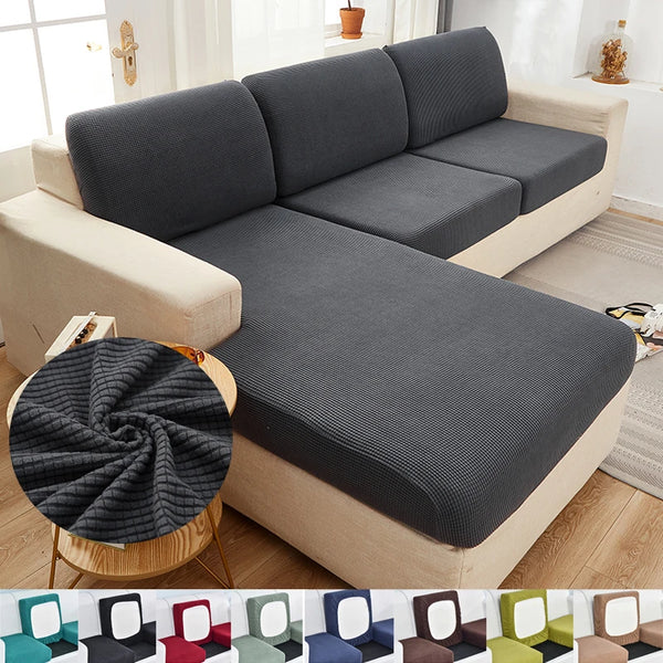 A gray stretch sofa seat cushion protector slipcover is shown on a light-colored sofa.