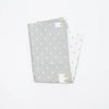 A stack of soft cotton baby pillow covers in light gray with yellow stitching details.